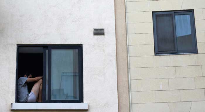 Exterior building view featuring a dark-framed Picture Windows Atlanta with a person sitting by the window, highlighting minimalist architecture, large fixed glass design, and urban residential window styling.