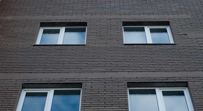 Exterior brick building facade with multiple white-framed Picture Windows Atlanta, featuring clean rectangular design, fixed glass panels, and modern residential architecture.