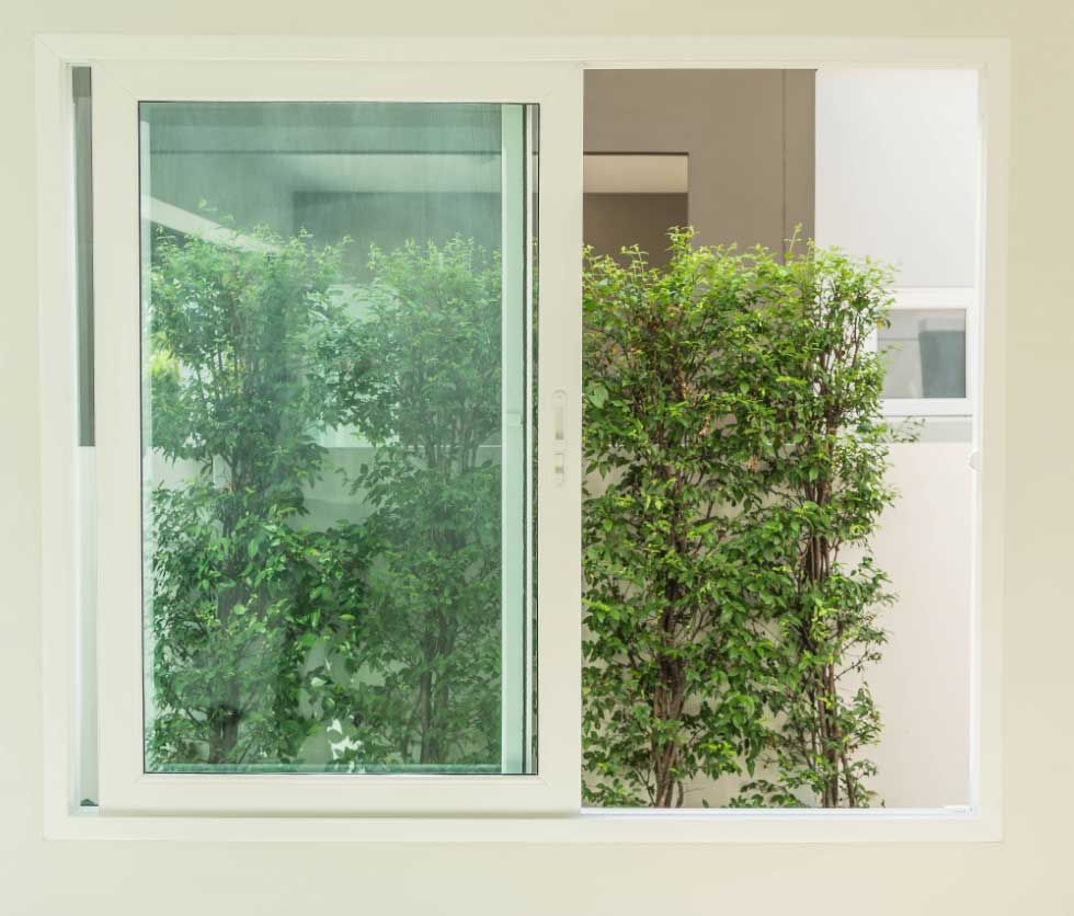 Interior view of sleek white-framed Sliding Windows Atlanta partially open to greenery outside, highlighting smooth sliding operation, natural light, and modern home window design.