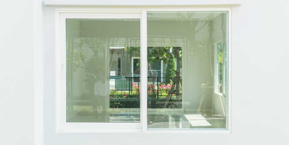 Clean white exterior wall featuring large glass Sliding Windows Atlanta, providing wide outdoor views, smooth sliding functionality, and a modern residential window installation.