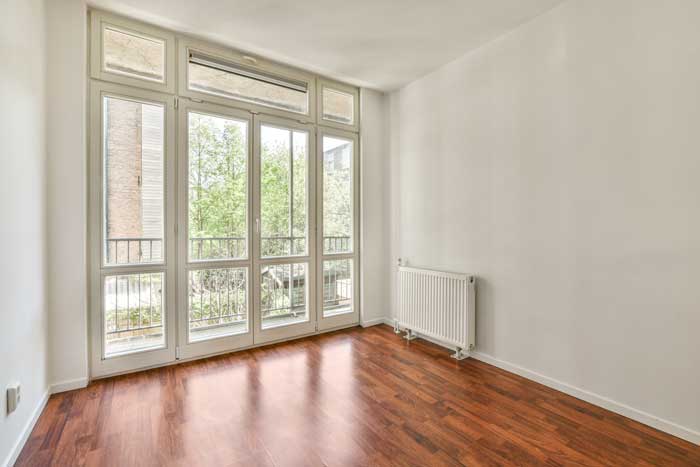 Bright empty living room with large floor-to-ceiling windows and balcony doors, featuring expert Window Replacement Gadsden, AL for modern residential interiors