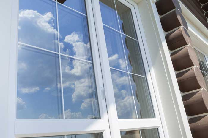 Close-up exterior view of white-framed double-pane windows reflecting blue sky and clouds, highlighting professional Window Replacement Ranburne, AL for energy-efficient homes