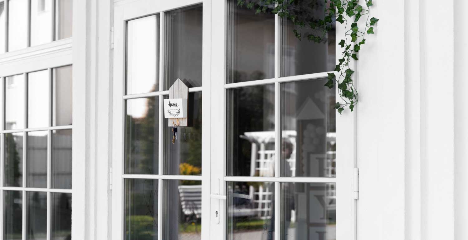 Close-up of white-framed French windows with decorative grid pattern and exterior greenery, showcasing professional Window Replacement Ranburne, AL for residential homes