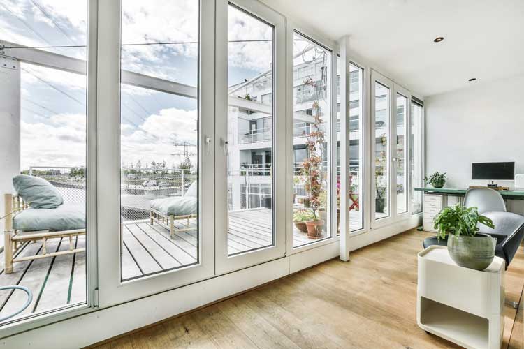 Bright contemporary living room with floor-to-ceiling glass doors leading to balcony, highlighting professional Window Replacement Roanoke, AL for modern residential window installations