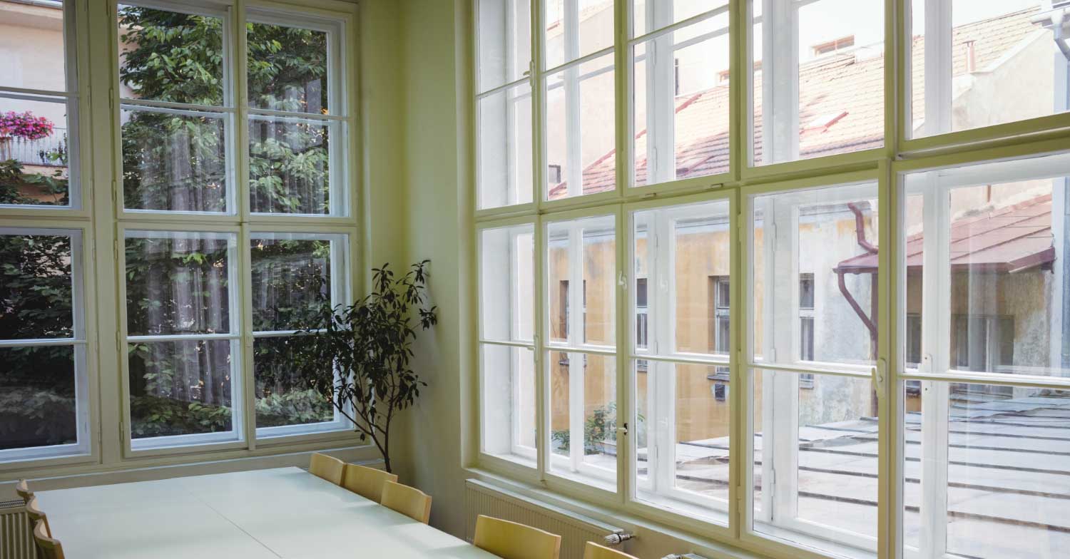 Bright interior room with large multi-pane white-framed windows providing natural light and courtyard view, highlighting professional Window Replacement Roanoke, AL for residential and commercial spaces