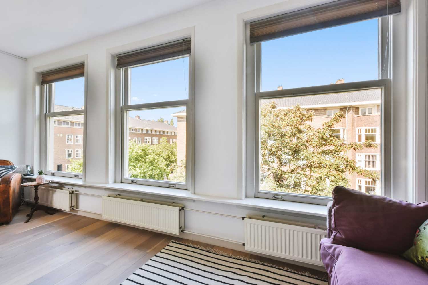 Bright living room with multiple tall white-framed windows providing natural light and neighborhood views, highlighting professional Window Replacement Wedowee, AL for residential window upgrades