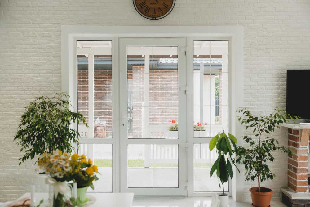 Bright living room with white-framed French doors and large glass panels opening to outdoor patio, highlighting professional Window Replacement Calhoun County for residential window and door upgrades