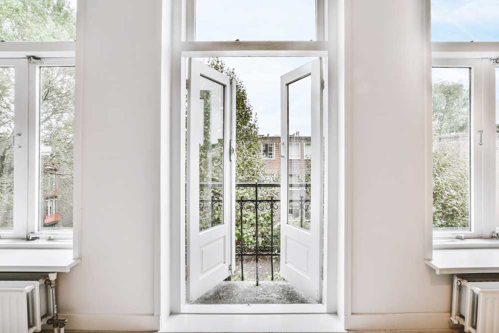 Bright interior with white-framed French windows opening to small balcony and greenery outside, highlighting professional Window Replacement Decatur for residential window and door upgrades