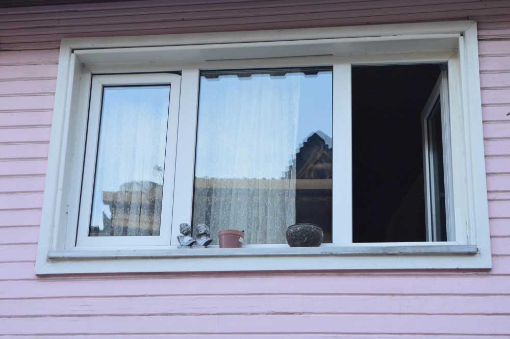 Exterior view of residential sliding window with white frame and partial opening, showcasing professional Window Replacement Decatur for durable and energy-efficient home window installations