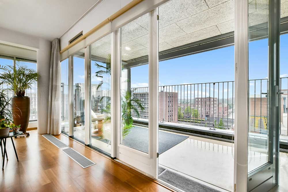Bright modern living room with large sliding glass doors opening to balcony and city view, highlighting professional Window Replacement Georgia for energy-efficient residential window upgrades